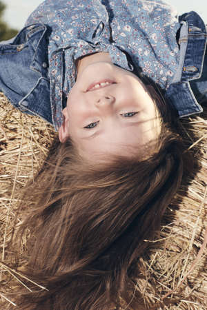 Portrait of a little girl upside down on a haystack. High quality photo