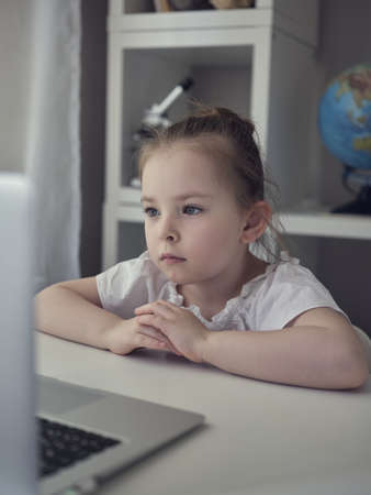 Cute little girl using laptop at home.の写真素材
