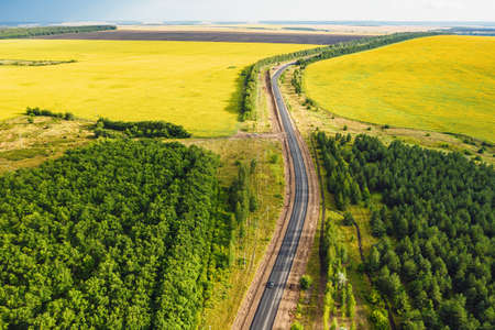 Aerial view of the road in mountain valley at sunset in autumn. Top view of asphalt roadway, car,...