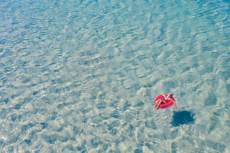 A child swims on a red inflatable circle. The concept of beach holidays and relaxation. Aerial. High quality photoの写真素材