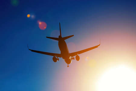 flying airplane silhouette in the blue skyの写真素材