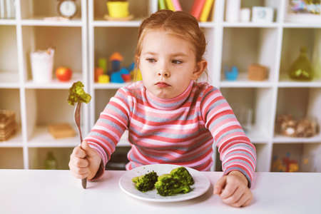Funny little girl eating broccoli using a fork. High quality photoの写真素材