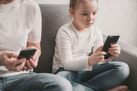 Mom and daughter are addicted to a smartphone. Harm of electronic devices for children. High quality...