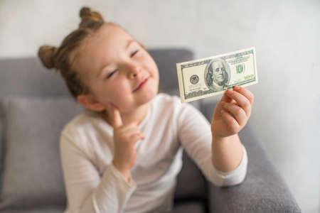 Cute little child girl with US Dollar bill as symbol of financial education. Selective focus. High quality photoの写真素材