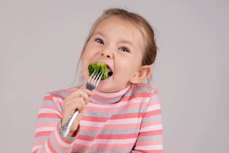 The child eats broccoli with undisguised disgust. High quality photoの写真素材