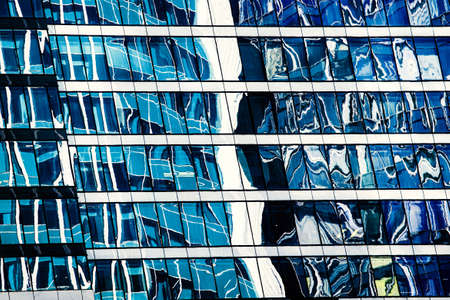 View of a modern glass skyscraper reflecting the blue sky blue . High quality photoの写真素材