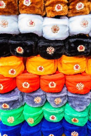 Rows of russian winter hats of different colors with army emblems at the street market at Old Arbat street in Moscow, iconic popular souvenir from Russia. High quality photoの写真素材