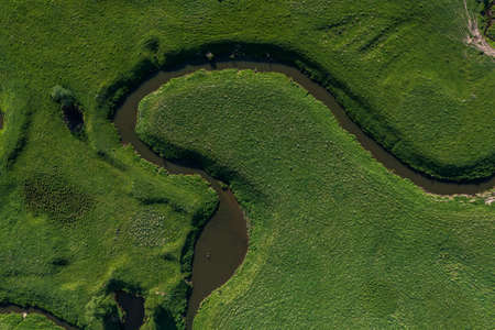 aerial landscape of winding river in green field, top view of beautiful nature texture from drone. High quality photoの写真素材