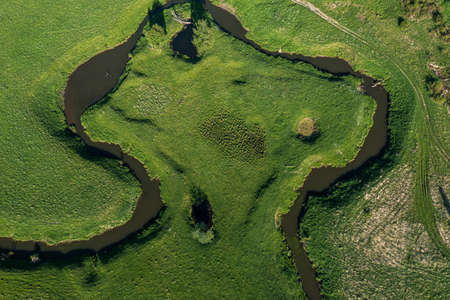 aerial landscape of winding river in green field, top view of beautiful nature texture from drone. High quality photoの写真素材
