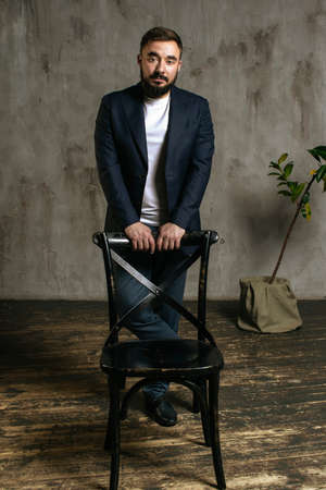 A young brutal bearded man in a suit stands in the studio. High quality photoの写真素材