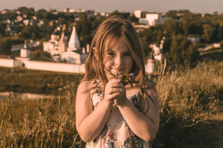 A little girl in the field with her hands up in the air. High quality photoの写真素材