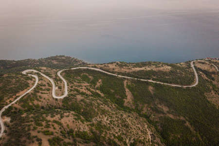 A long and winding road passing through green hills. High quality photoの写真素材