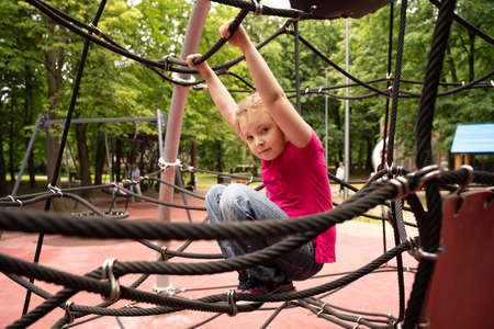 Happy teenager girl child playing in rope spider web at playground. Children. High quality photoの写真素材