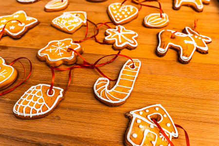 Wooden background with lots of gingerbread Christmas gingerbread in the shape of a house, heart. Deer. star, christmas tree toy, ball with white glaze. High quality photoの写真素材