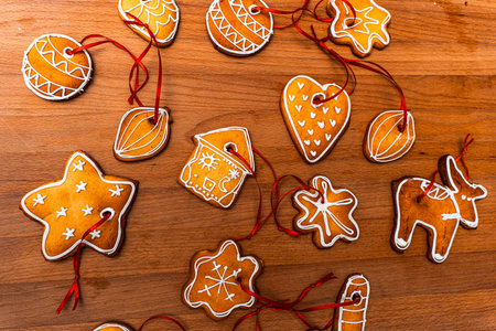 Wooden background with lots of gingerbread Christmas gingerbread in the shape of a house, heart. Deer. star, christmas tree toy, ball with white glaze. High quality photoの写真素材