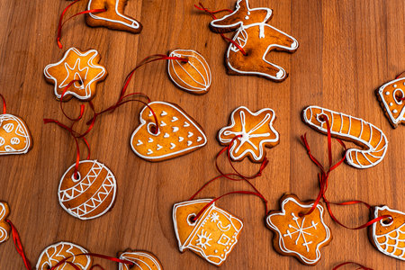 Wooden background with lots of gingerbread Christmas gingerbread in the shape of a house, heart. Deer. star, christmas tree toy, ball with white glaze. High quality photoの写真素材