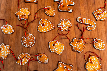 Wooden background with lots of gingerbread Christmas gingerbread in the shape of a house, heart. Deer. star, christmas tree toy, ball with white glaze. High quality photoの写真素材
