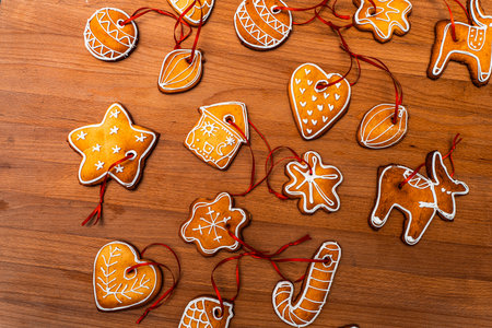 Wooden background with lots of gingerbread Christmas gingerbread in the shape of a house, heart. Deer. star, christmas tree toy, ball with white glaze. High quality photoの写真素材