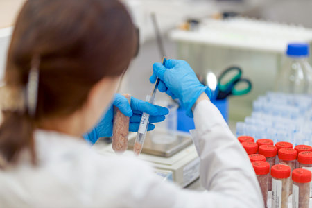 A chemical laboratory employee wearing medical gloves examines samples and takes an analysis. The...