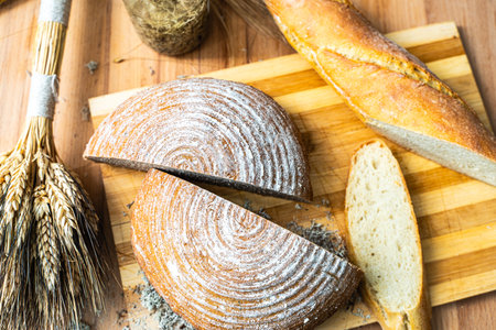 Bread and baguette cut on a wooden board with ears of wheat. Selected Focus. High quality photoの写真素材