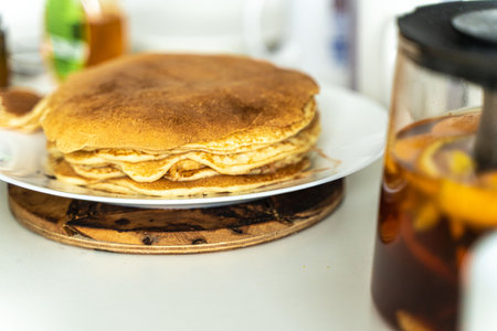Delicious breakfast with freshly baked pancakes and citrus tea in a teapot. Homemade breakfast concept. Selected focus. High quality photoの写真素材