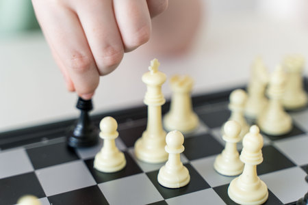 A child's hand holds a chess piece. Ira in chess. Close-up. Selected Focus. High quality photo