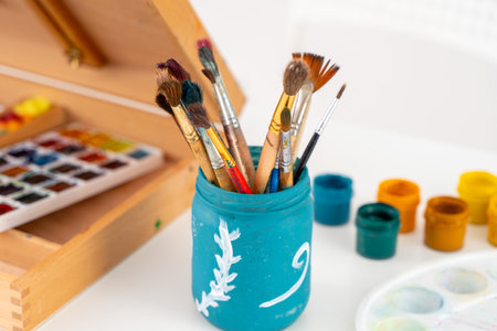Art brushes, an easel with watercolors and gouache. A place for the artists creativity. Selected Focus. High quality photoの写真素材