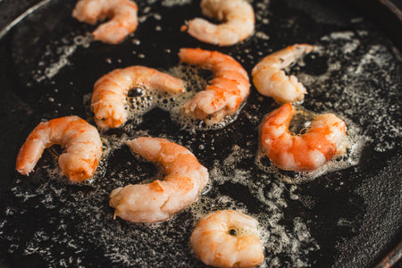 The shrimp is fried in oil in a cast-iron skillet. Large king prawns close-up. Selected focus. High quality photoの写真素材
