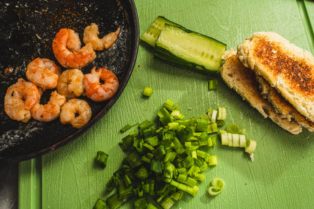 Pan fried shrimp next to chopped onion, cucumber and toast. Ingredients for cooking a Mediterranean dish. Selected focus. High quality photoの写真素材