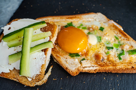 Breakfast of warmed toast, egg, cheese, green onions and cucumber. Beautiful serving of toast for breakfast. Selected focus. High quality photoの写真素材