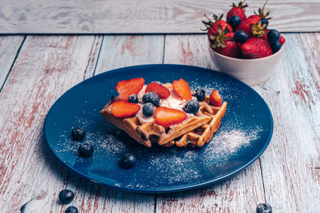 Belgian waffles with blueberries sprinkled with powdered sugar on a plate. High quality photoの写真素材