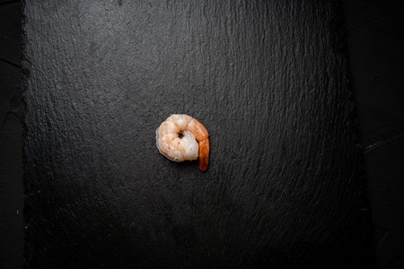 One boiled, frozen shrimp on a black mica board. Place for text. High quality photoの写真素材