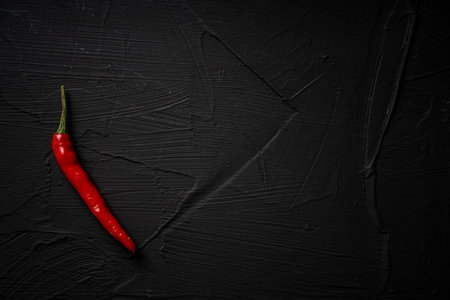 Pod of red, hot, chili pepper on a black background. Place for text. High quality photoの写真素材