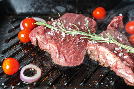 Raw meat, steak is pan-fried or grilled with vegetables, cherry tomatoes and onions. High quality photoの写真素材