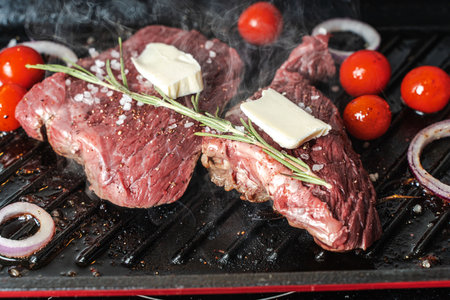 Cooking meat or steak. Raw meat with vegetables and cherry tomatoes with rosemary and sea salt in a pan or grill. Close-up. High quality photoの写真素材