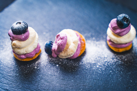The cake lost its shape next to the two well-standing. Mini desserts on a black mica board with...