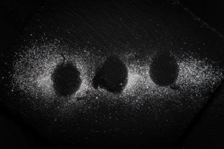White powdered sugar is poured on a black mica board. Background. High quality photoの写真素材
