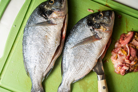 Gutted dorado fish with knife and giblets on a green cutting board background. High quality photo