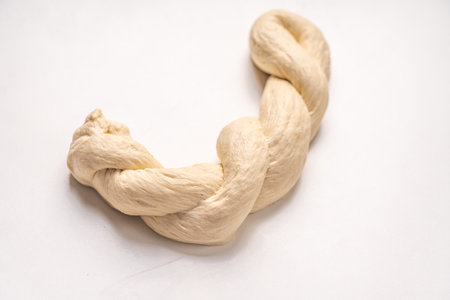The dough is braided on a white background. The process of preparing baked goods. High quality photoの写真素材