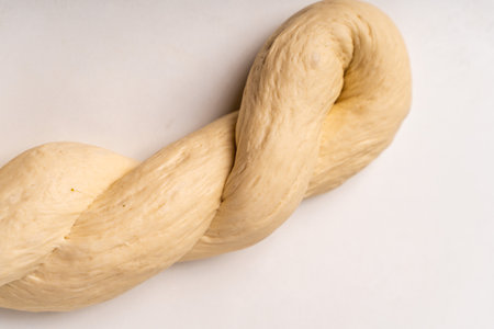 The dough is braided on a white background. The process of preparing baked goods. High quality photoの写真素材