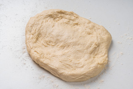 Yeast dough for a pie or pizza on a white table with flour. Pizza cooking process, recipe. High quality photoの写真素材