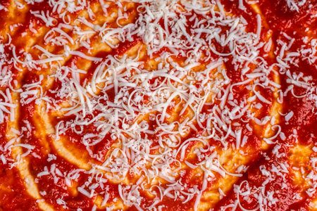 The pizza dough circle is topped with spiral tomato sauce and grated cheese. The process of making...