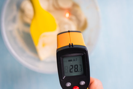 A pyrometer measures the temperature of white molten chocolate. High quality photo