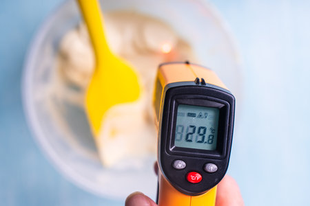 A thermometer measures the temperature of white molten chocolate. High quality photoの写真素材