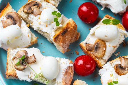 Mini toast with cottage cheese, quail eggs, cherry tomatoes, mushrooms and microgreens on a blue plate. High quality photoの写真素材