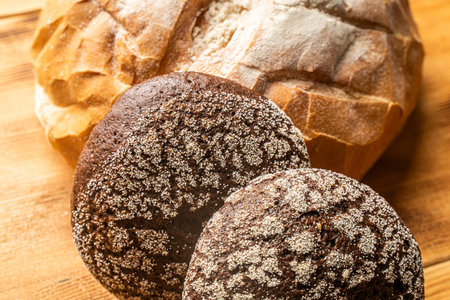 Round wheat bread and small rye bread rolls on a wooden background. Space for text. High quality photoの写真素材
