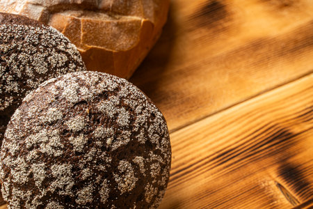Round wheat bread and small rye bread rolls on a wooden background. Space for text. High quality photoの写真素材