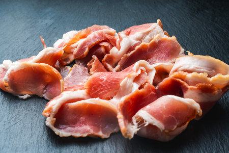 Raw bacon cut into thin slices on a black mica board. High quality photoの写真素材