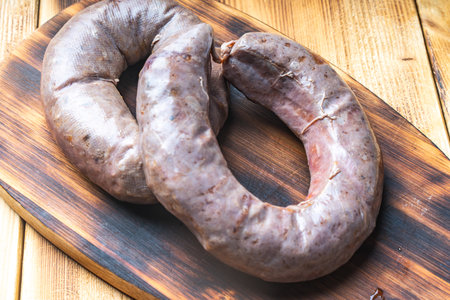 Homemade sausage on a wooden board and a background with cherry tomatoes. High quality photoの写真素材