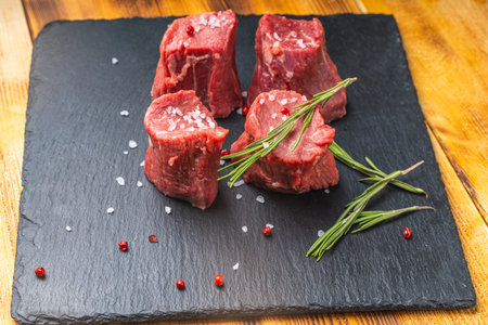 Raw filet mignon steaks with coarse salt and rosemary on a black mica board on a wooden background. High quality photoの写真素材
